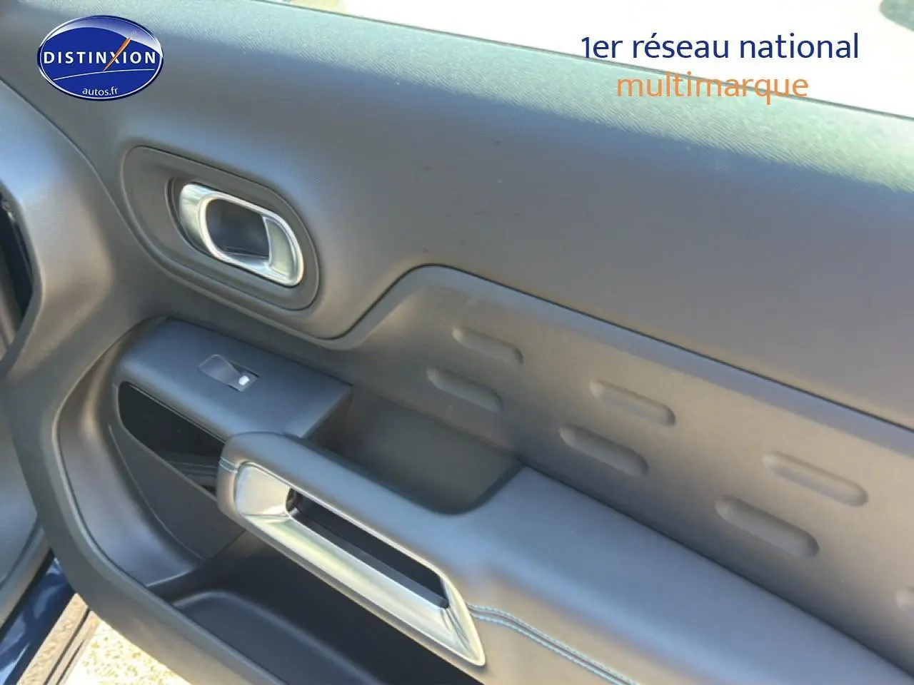 Gros plan sur la porte côté gauche du Citroën C5 Aircross bleu eclipse, avec poignée intérieure chromée et commande de vitre.