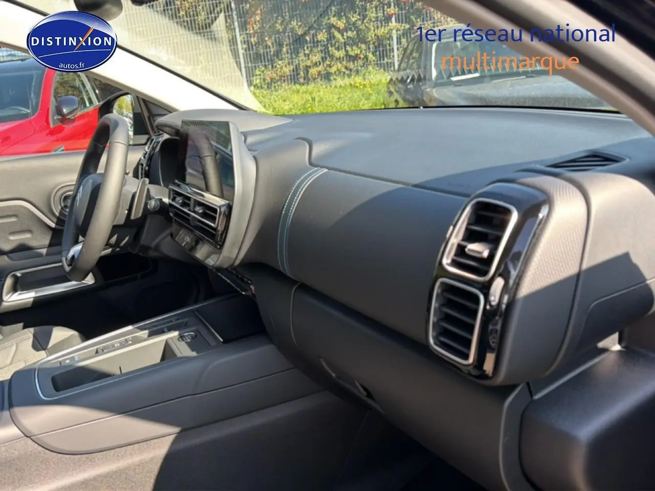 Intérieur du Citroën C5 Aircross 2025 vu côté passager, tableau de bord noir avec surpiqûres bleues et écran tactile central.