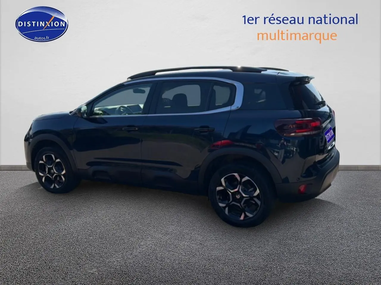 Vue latérale gauche d'un Citroën C5 Aircross bleu eclipse avec jantes alu et barres de toit noires.