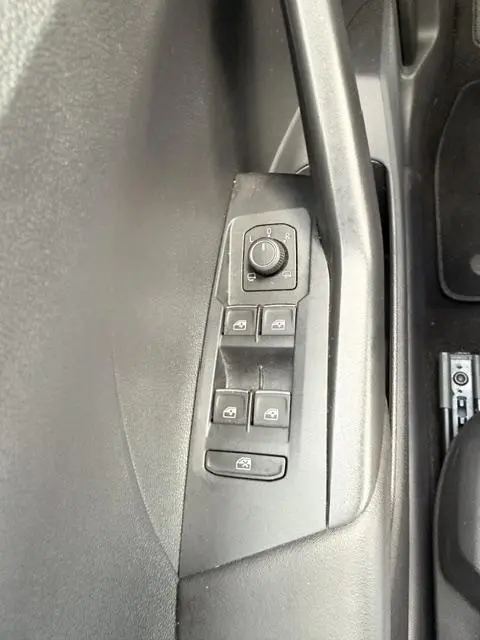 Détail des commandes de lève-vitres et réglage des rétroviseurs sur la porte côté gauche du Volkswagen T-Cross gris foncé.