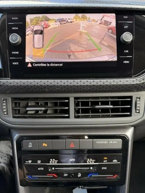 Affichage caméra de recul sur écran tactile du tableau de bord d’un Volkswagen T-Cross gris foncé, avec commandes climatisation et ventilation visibles.