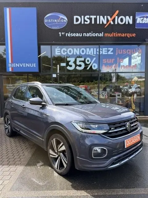 Vue 3/4 avant d'un Volkswagen T-Cross gris foncé R-Line Tech 2023 avec jantes alliage et badge R-Line visible.