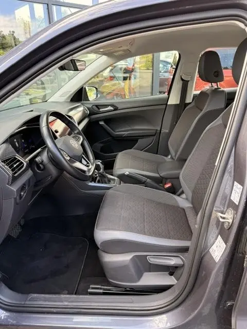 Vue intérieure côté conducteur du Volkswagen T-Cross gris foncé 2023, sièges tissu Hexalink et tableau de bord digital.