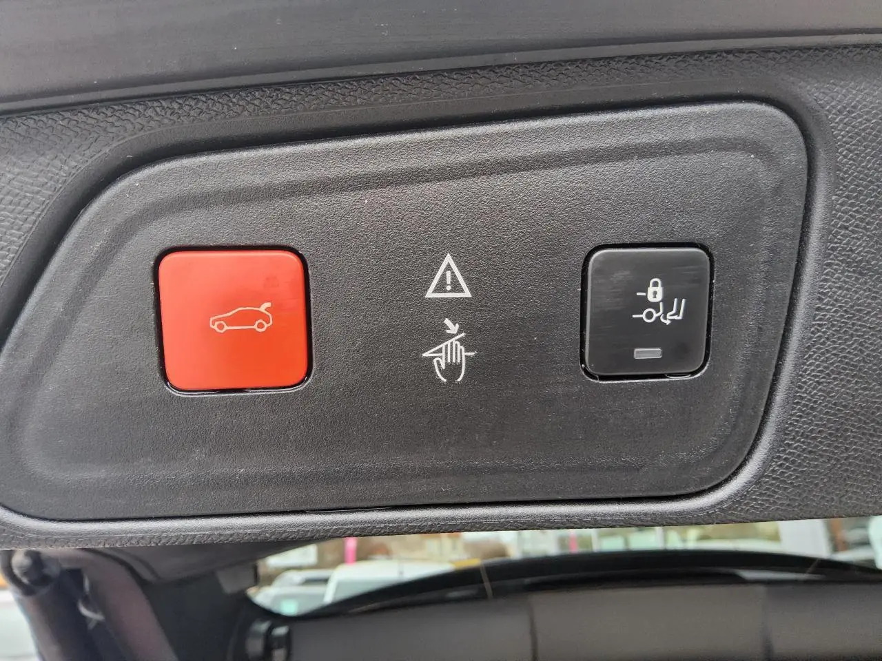 Gros plan sur les boutons de commande du hayon mains libres du Peugeot 3008 rouge foncé, intérieur du coffre visible.