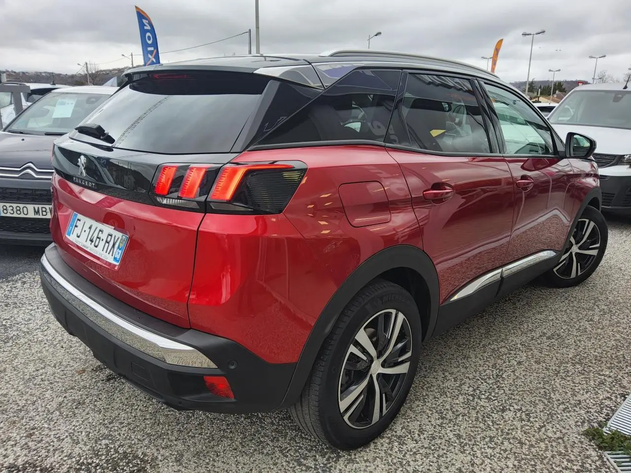 Vue 3/4 arrière droite du Peugeot 3008 rouge foncé avec toit noir et jantes alliage bi-ton diamantées.