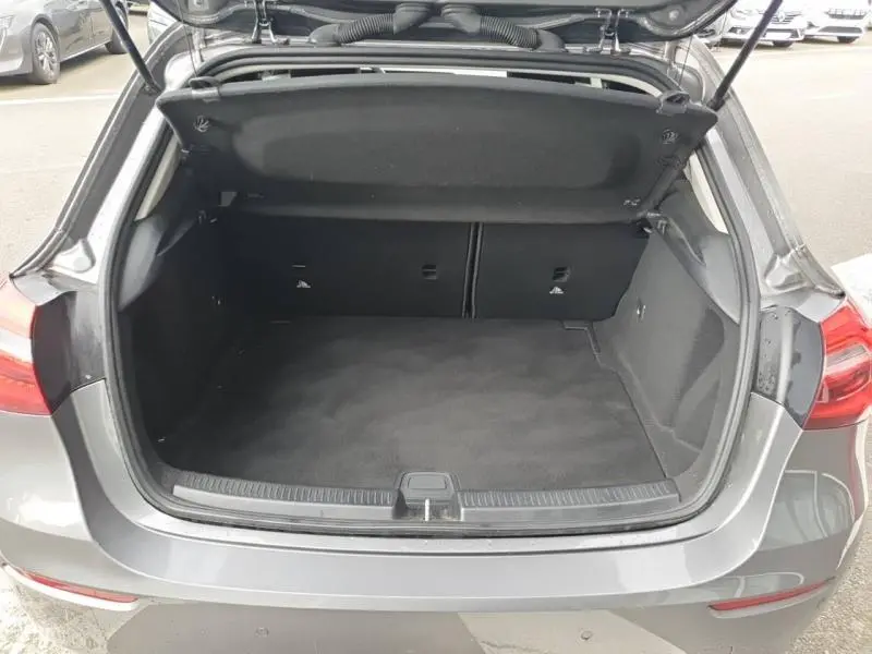 Coffre ouvert vu de l'arrière d'une Mercedes Classe A 160 gris montagne métallisé, intérieur noir spacieux et propre.