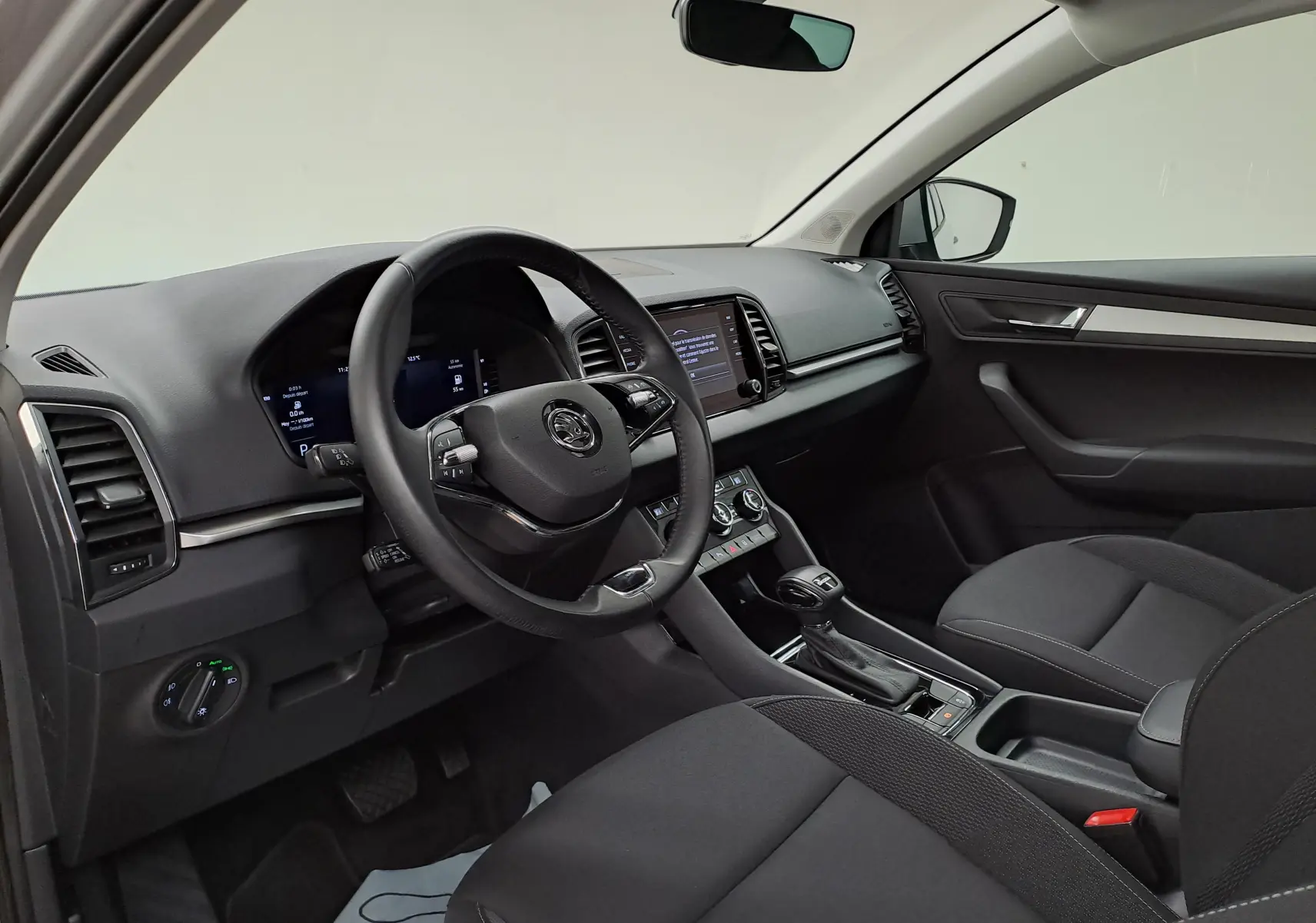 Vue intérieure côté conducteur du Skoda Karoq 2023, tableau de bord moderne avec Digital Cockpit et console centrale noire.