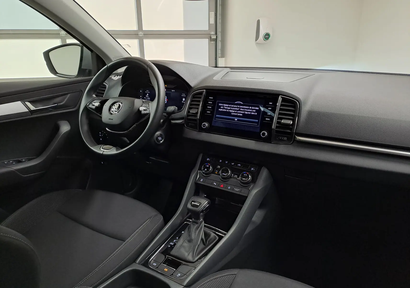 Vue intérieure côté conducteur du Skoda Karoq gris perle 2023, mettant en valeur le tableau de bord digital et la console centrale avec boîte automatique.