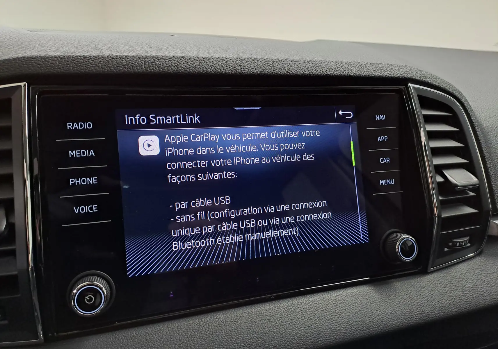 Écran tactile central du Skoda Karoq 2023 affichant les options Apple CarPlay, entouré de commandes noires.