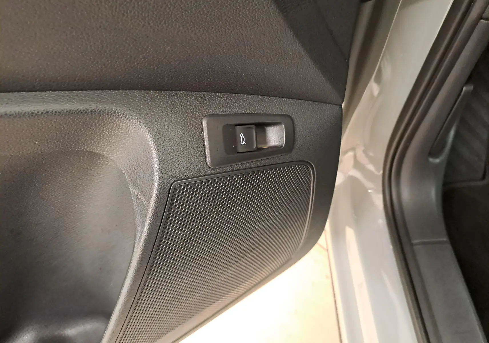 Détail de la commande d'ouverture du coffre sur la porte côté gauche d'un Skoda Karoq gris perle 2023.