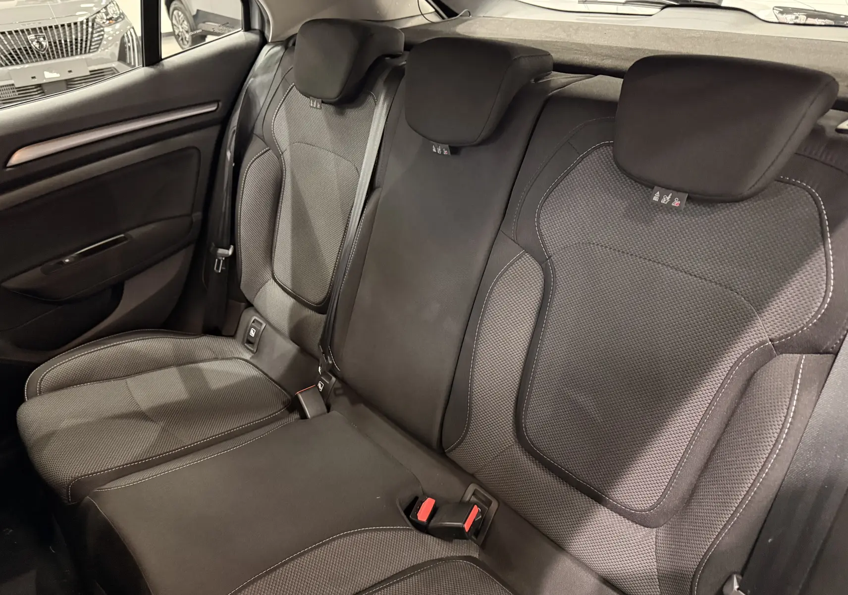 Vue intérieure des sièges arrière en tissu gris foncé de la Renault Mégane IV 1.5 dCi 115 Evolution, avec appuie-têtes et ceintures visibles.