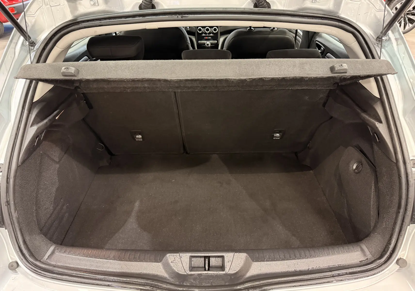 Coffre ouvert vu de l'arrière d'une Renault Mégane IV gris Highland, montrant l'espace de chargement et la plage arrière.