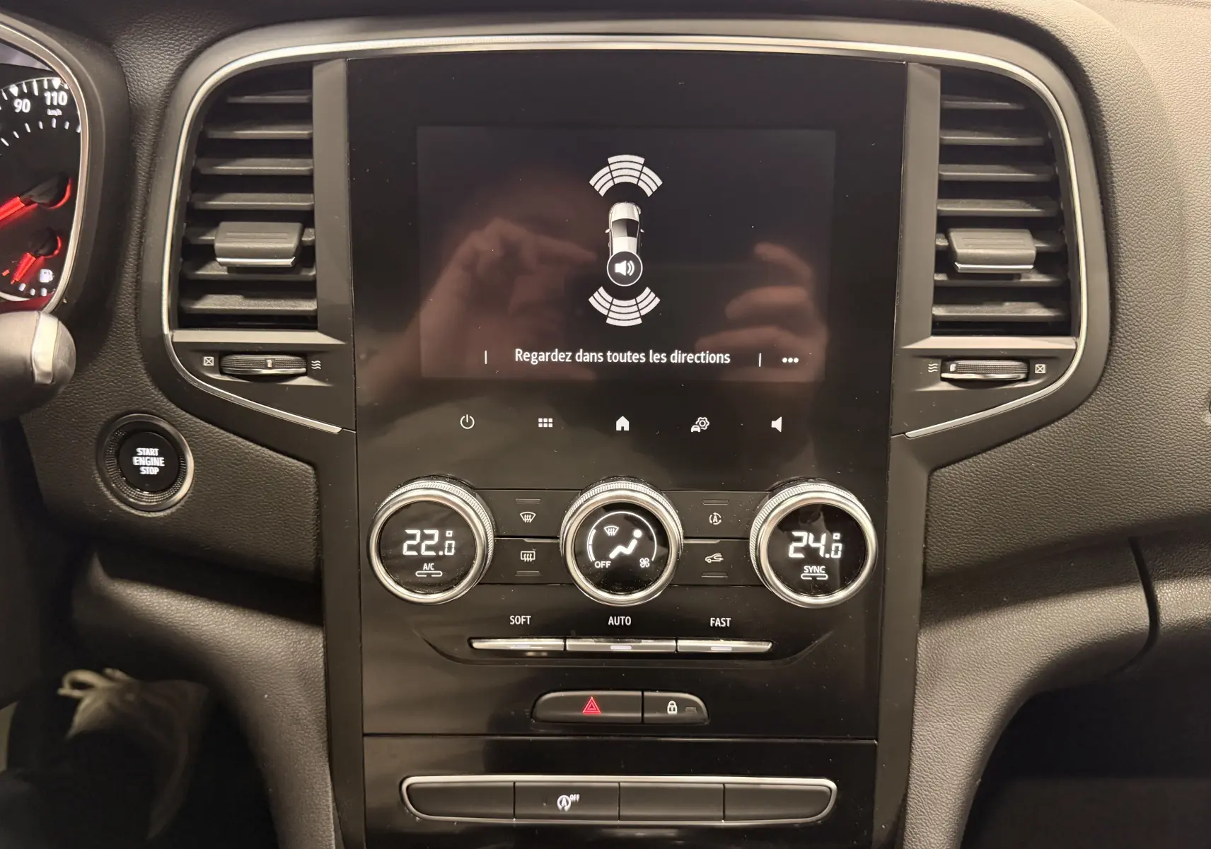 Vue centrale du tableau de bord de la Renault Mégane IV gris Highland, avec écran tactile et commandes de climatisation.