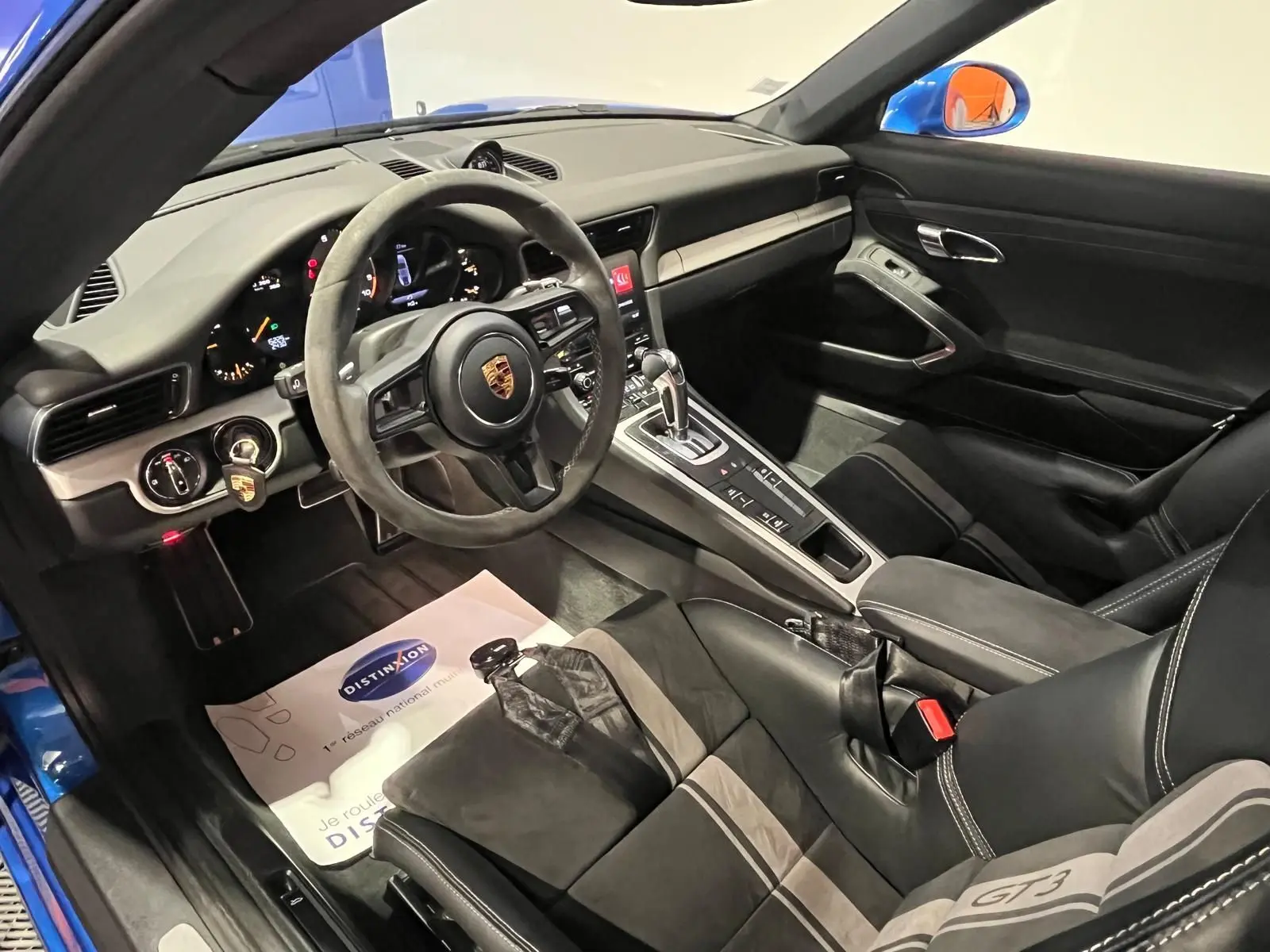 Vue intérieure côté conducteur de la Porsche 911 GT3 bleu saphir, volant sport alcantara et sièges baquets GT3.
