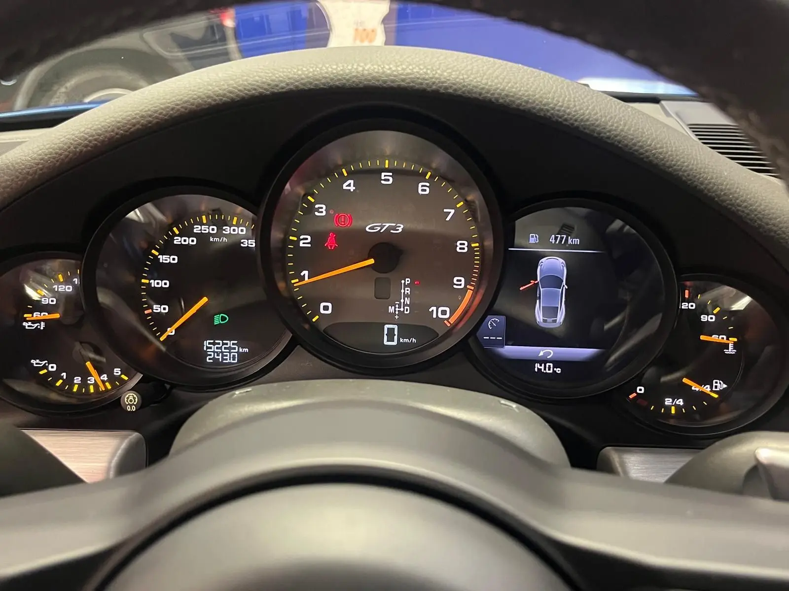 Vue rapprochée du tableau de bord de la Porsche 911 GT3, affichant le compteur central GT3 et l'écran digital.