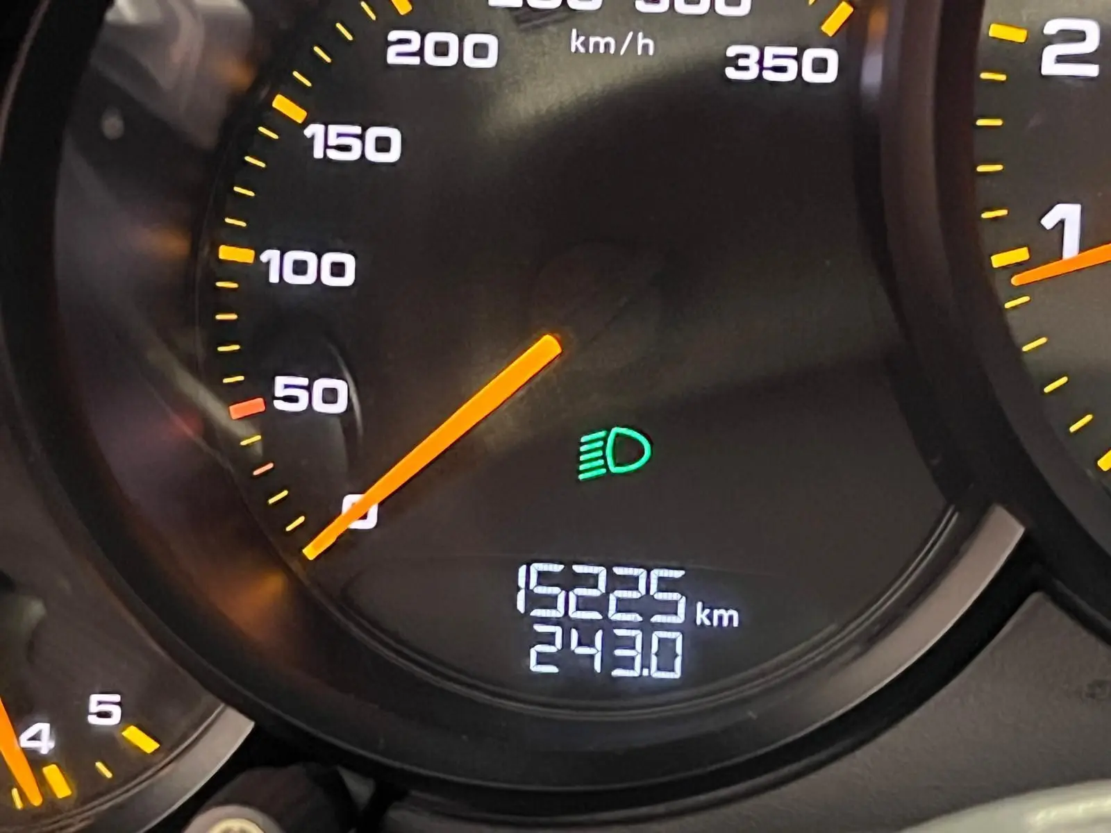 Gros plan sur le compteur de vitesse de la Porsche 911 GT3 affichant 15 225 km et témoin des feux de route allumé.
