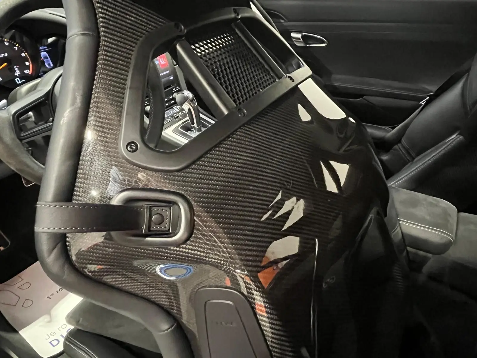 Gros plan sur le siège baquet sport en carbone côté conducteur de la Porsche 911 GT3, avec volant et console visibles en arrière-plan.