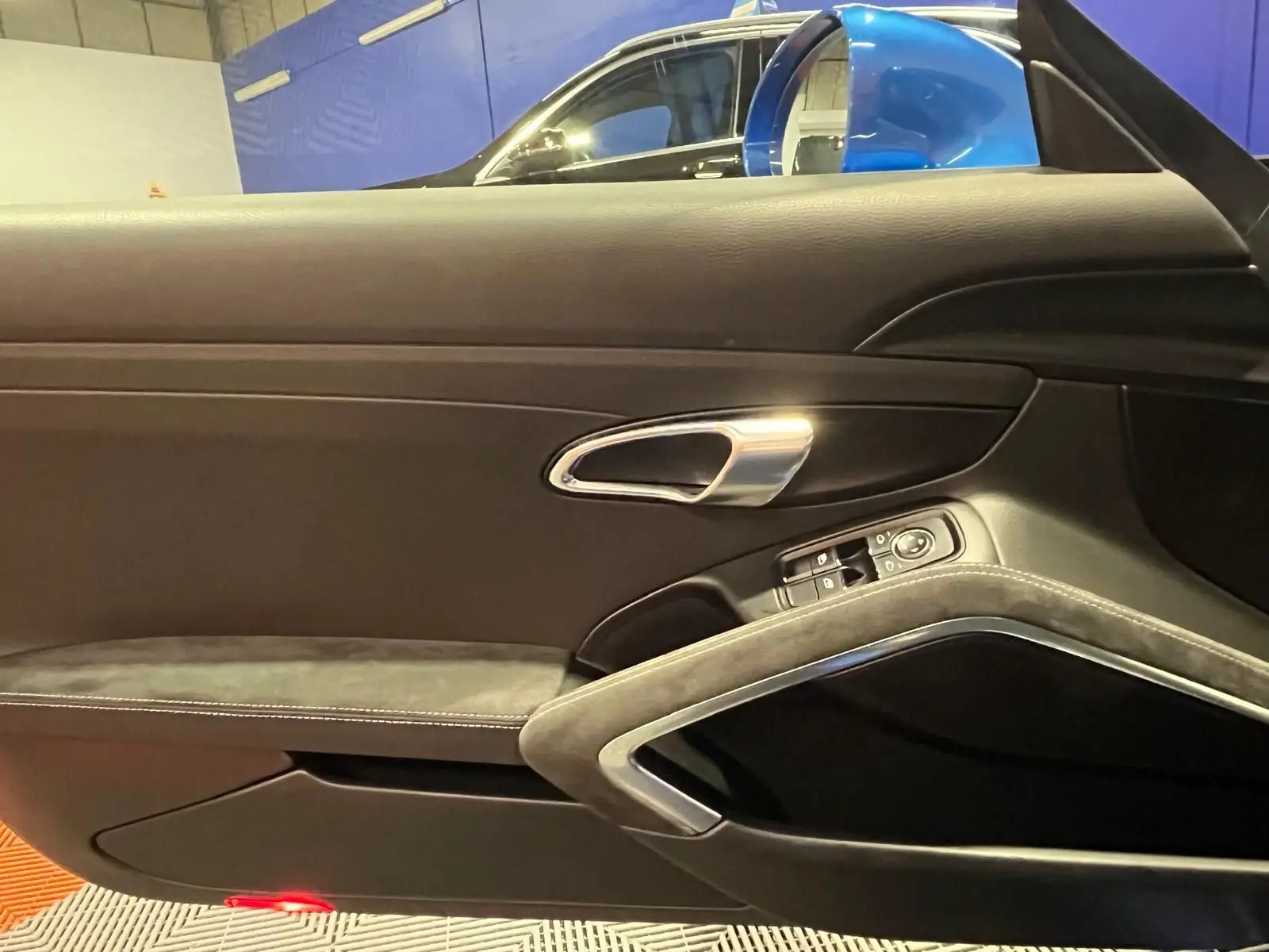Vue intérieure sur la porte côté gauche d’une Porsche 911 GT3 bleu saphir, avec poignée alu et garniture alcantara.