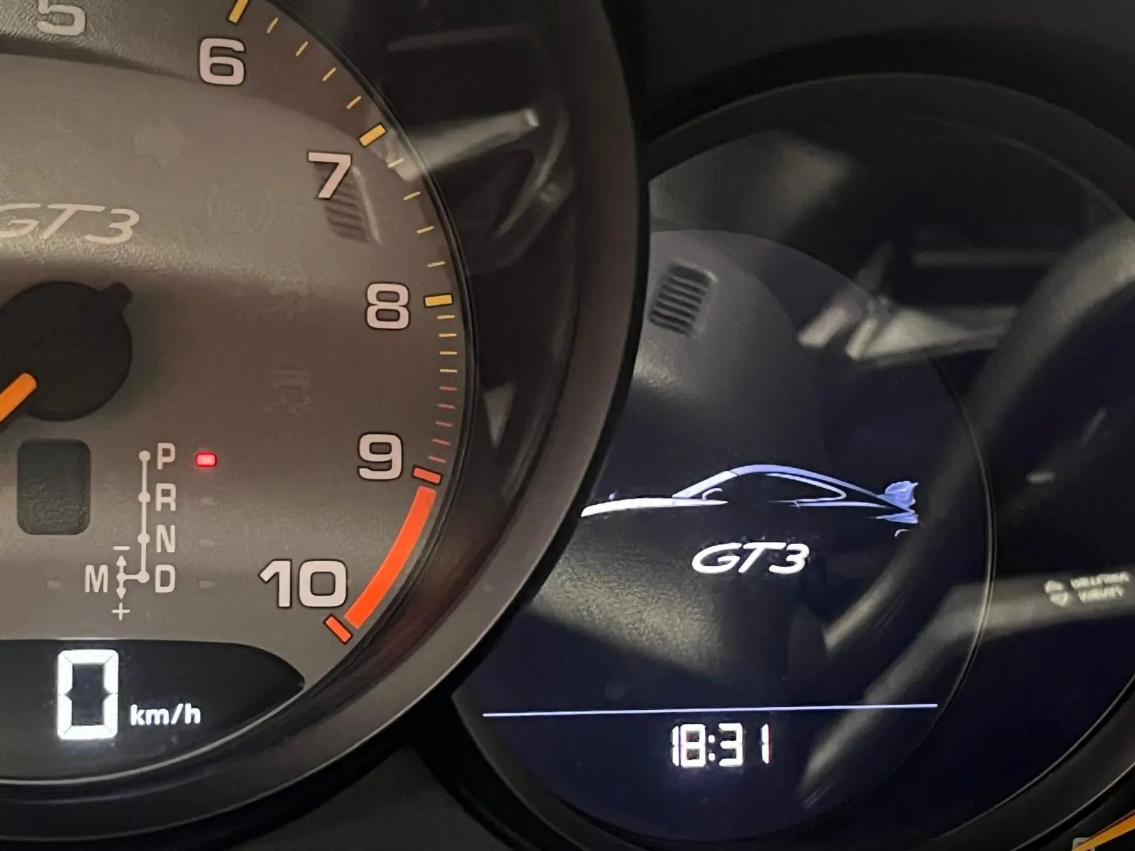 Gros plan sur le tableau de bord de la Porsche 911 GT3 avec compte-tours et affichage digital GT3 à 18h31.