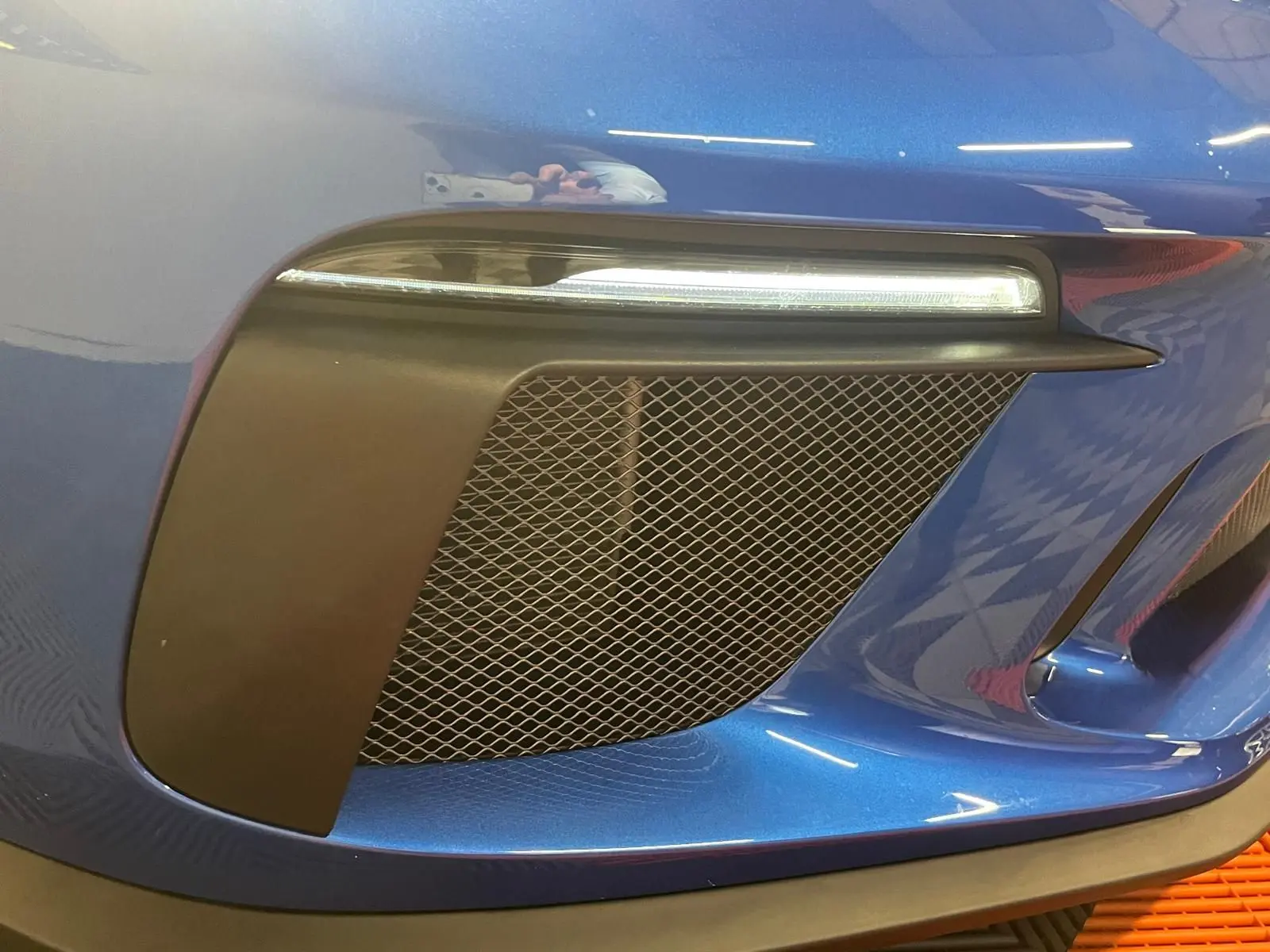 Gros plan sur la prise d'air avant droite et le feu LED d'une Porsche 911 GT3 bleu saphir.