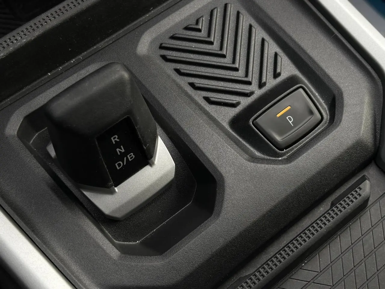 Gros plan sur la commande de boîte automatique et bouton de parking du Dacia Bigster blanc Banquise, intérieur noir.