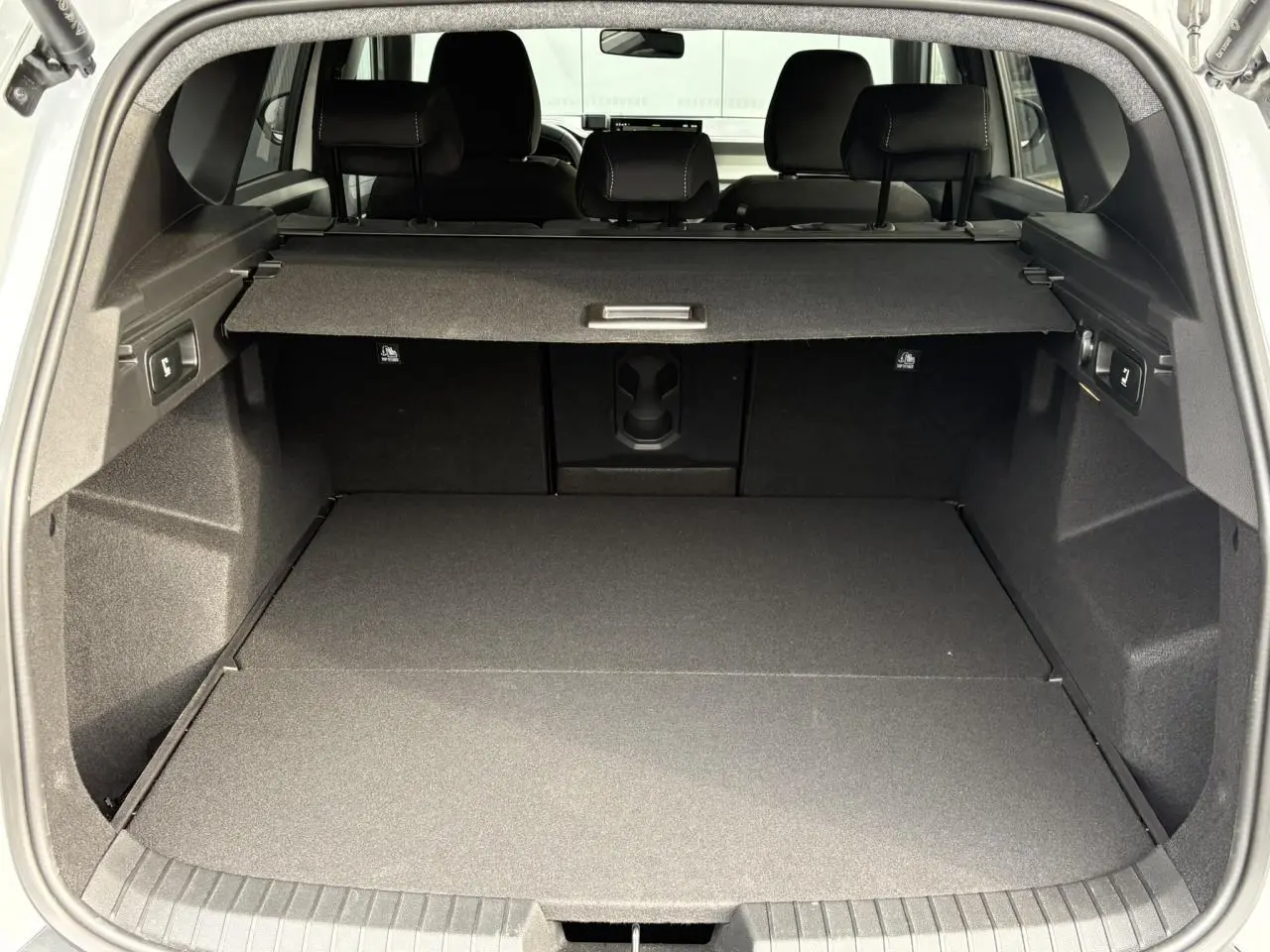 Coffre ouvert du Dacia Bigster blanc Banquise, vue arrière montrant un espace de chargement spacieux et bien fini.