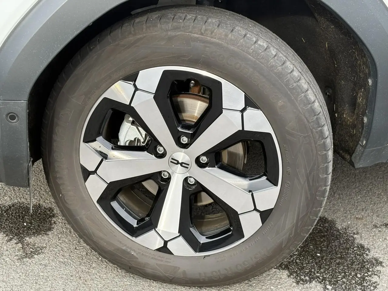 Gros plan sur la jante alliage diamantée 18 pouces du Dacia Bigster blanc Banquise, avec pneu Continental.