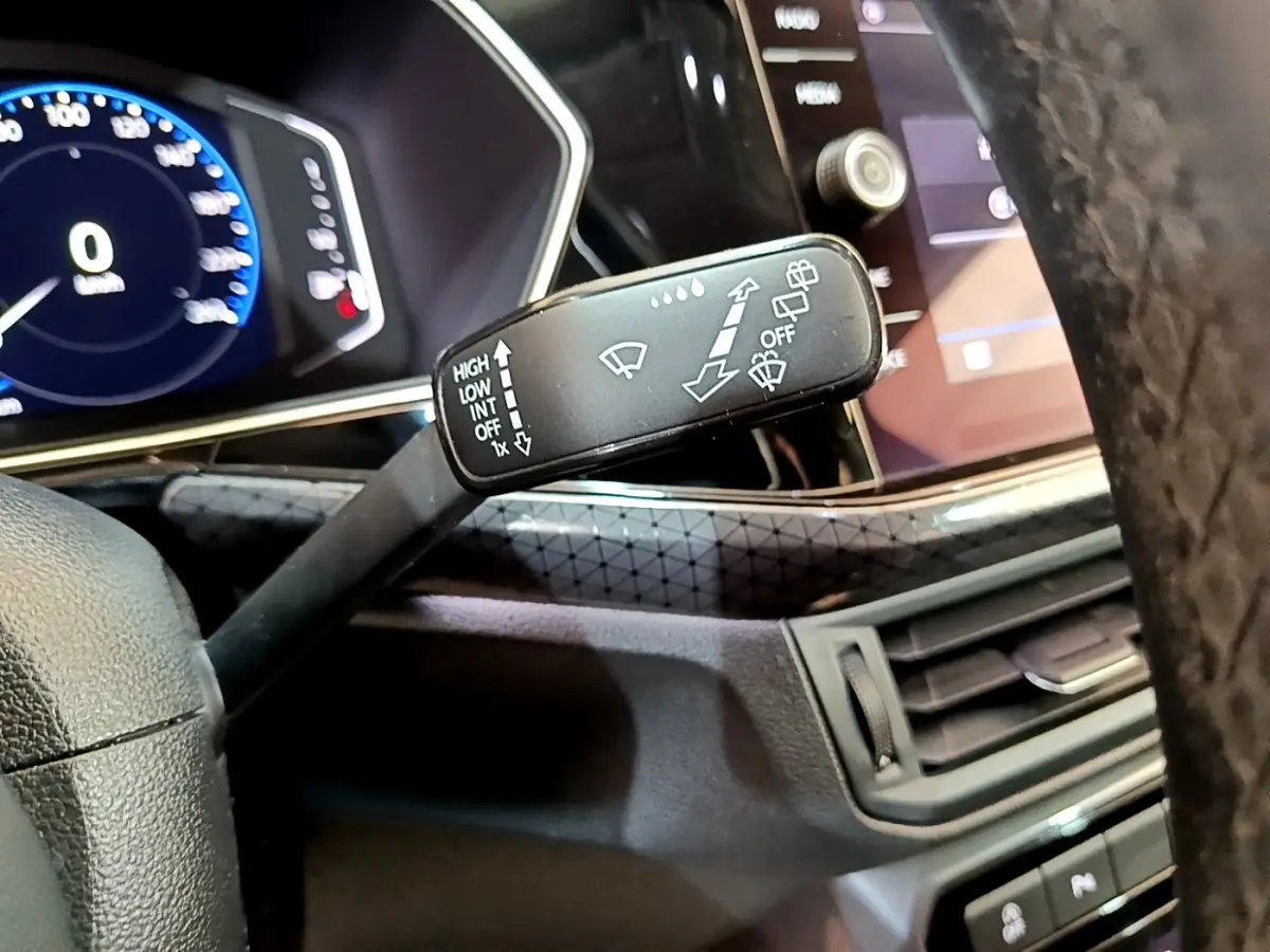 Gros plan sur la manette d’essuie-glace à gauche du volant dans l’habitacle noir du Volkswagen T-Cross 2022.