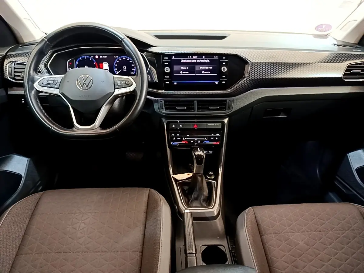 Vue intérieure avant du Volkswagen T-Cross 2022 noir, montrant le volant multifonctions, tableau de bord digital et console centrale.