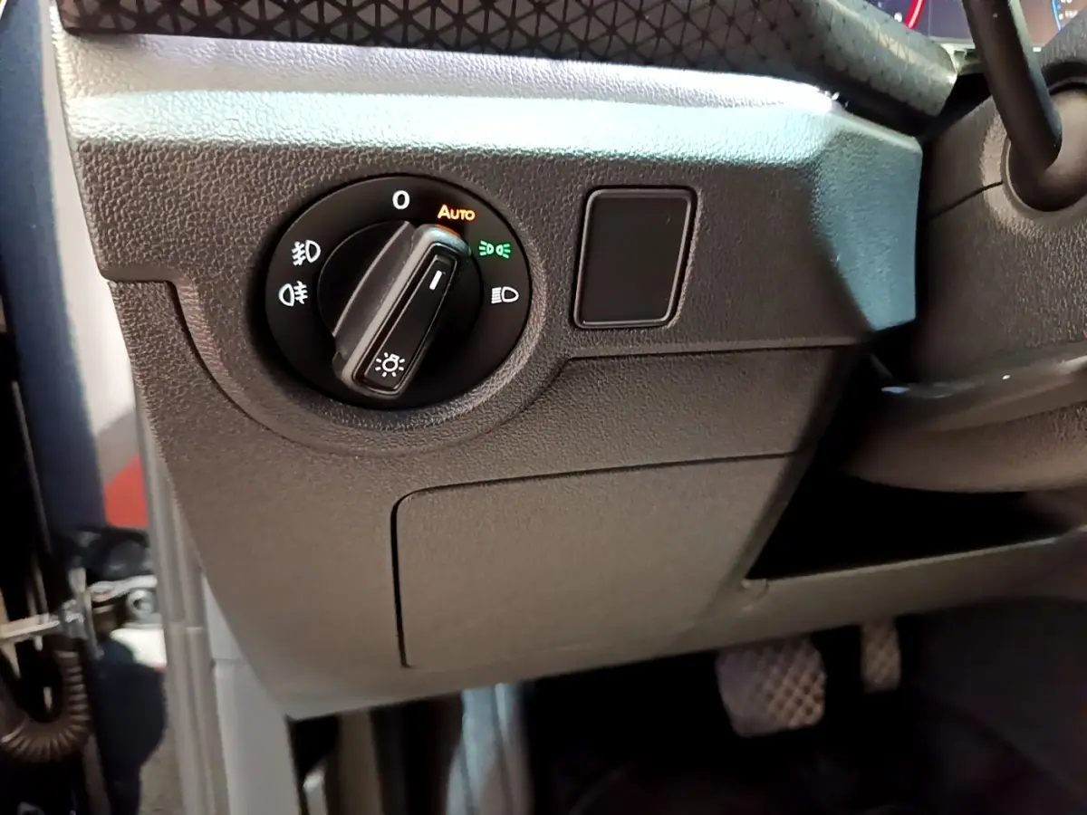 Gros plan sur le bouton de commande des phares à gauche du volant dans l'habitacle du Volkswagen T-Cross noir.