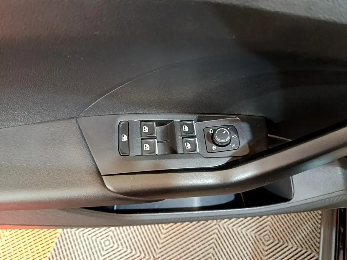 Gros plan sur la commande des vitres et réglage des rétroviseurs côté conducteur d’un Volkswagen T-Cross noir.