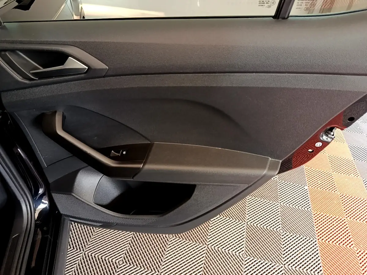 Intérieur de la porte côté conducteur du Volkswagen T-Cross noir, avec commande de vitre et poignée intégrée.