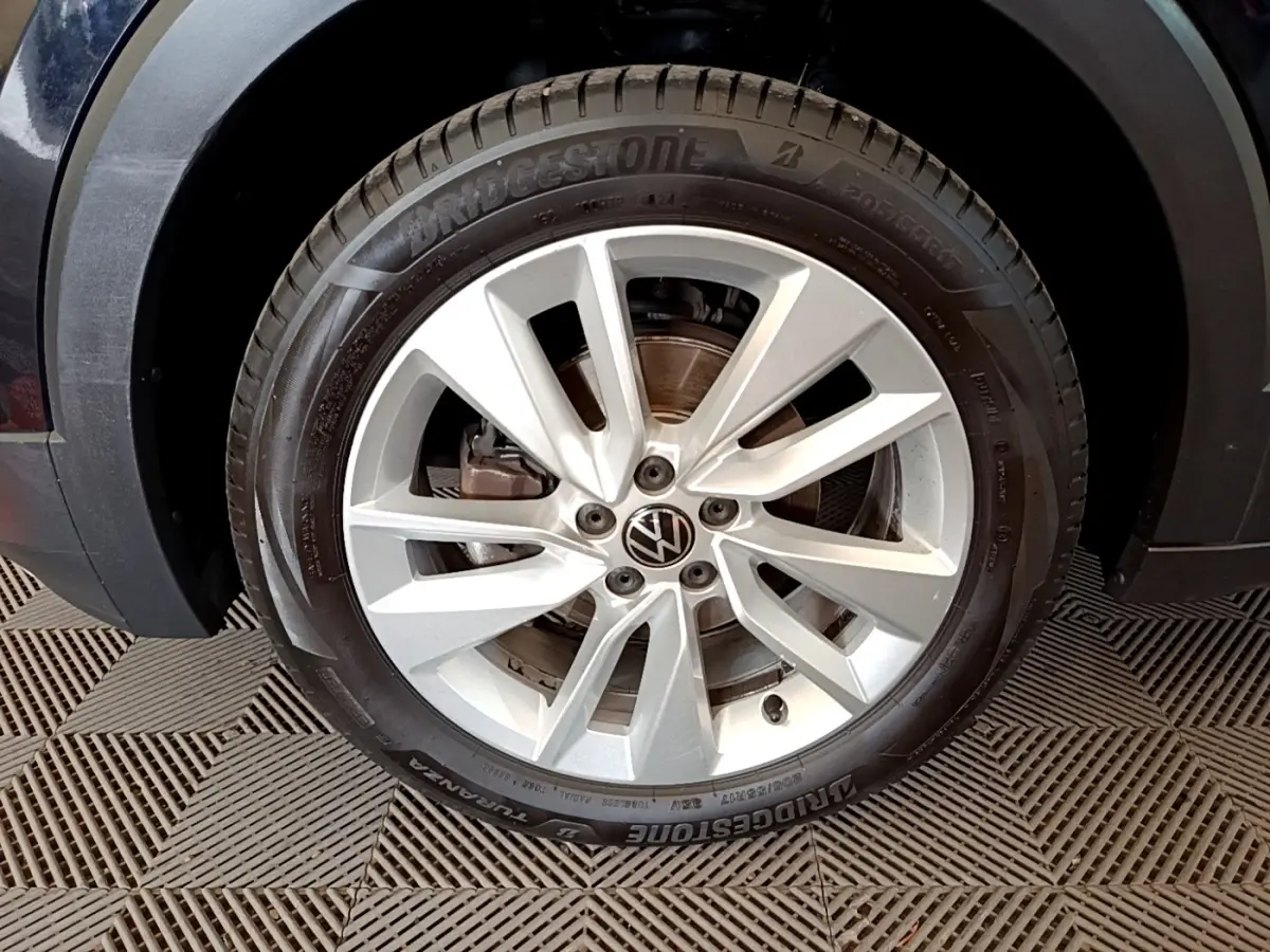 Gros plan sur la roue avant gauche du Volkswagen T-Cross noir, jante alliage argentée à plusieurs branches.