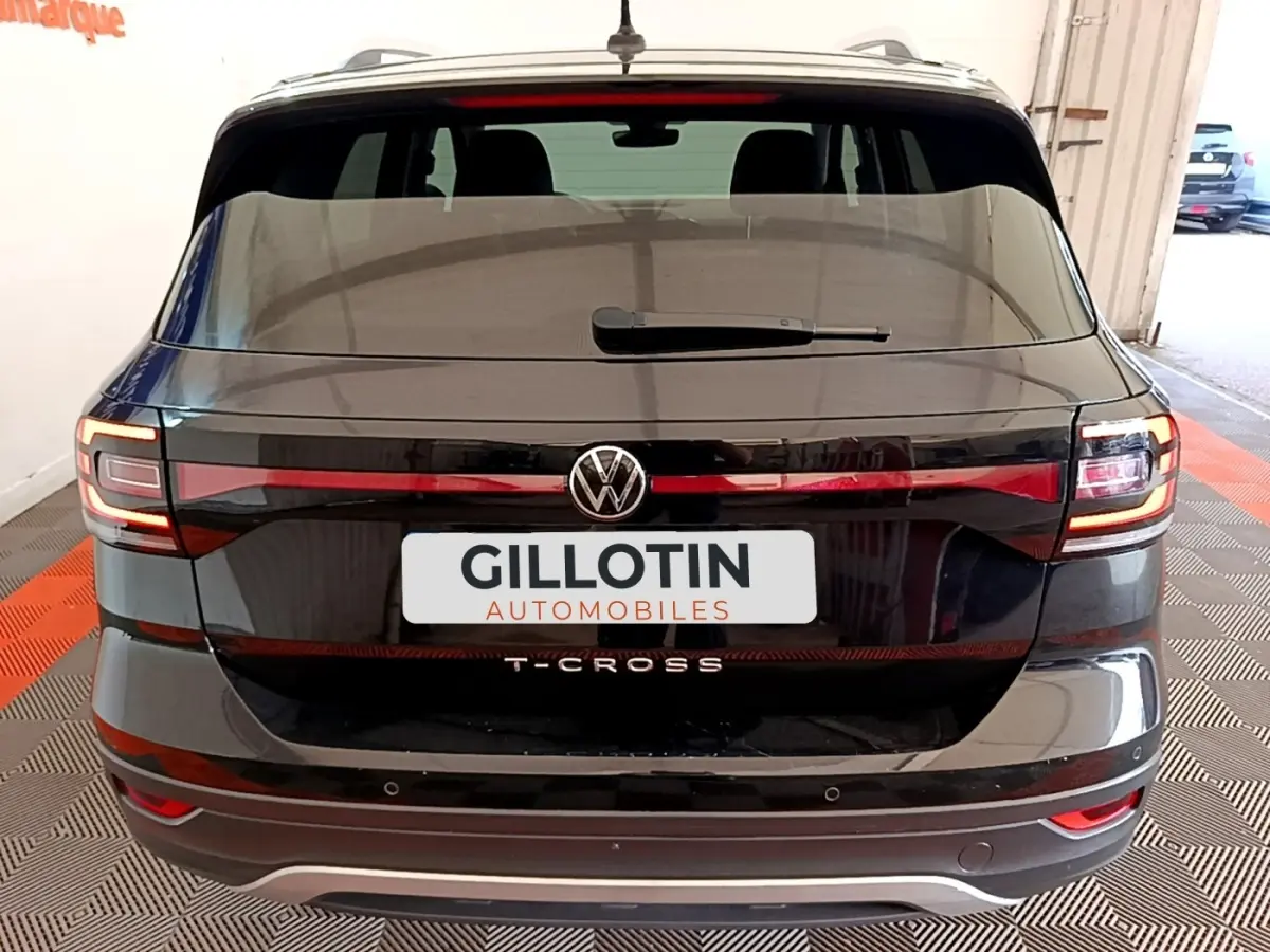 Vue arrière du Volkswagen T-Cross noir 2022 avec feux LED et logo central visible dans un garage.
