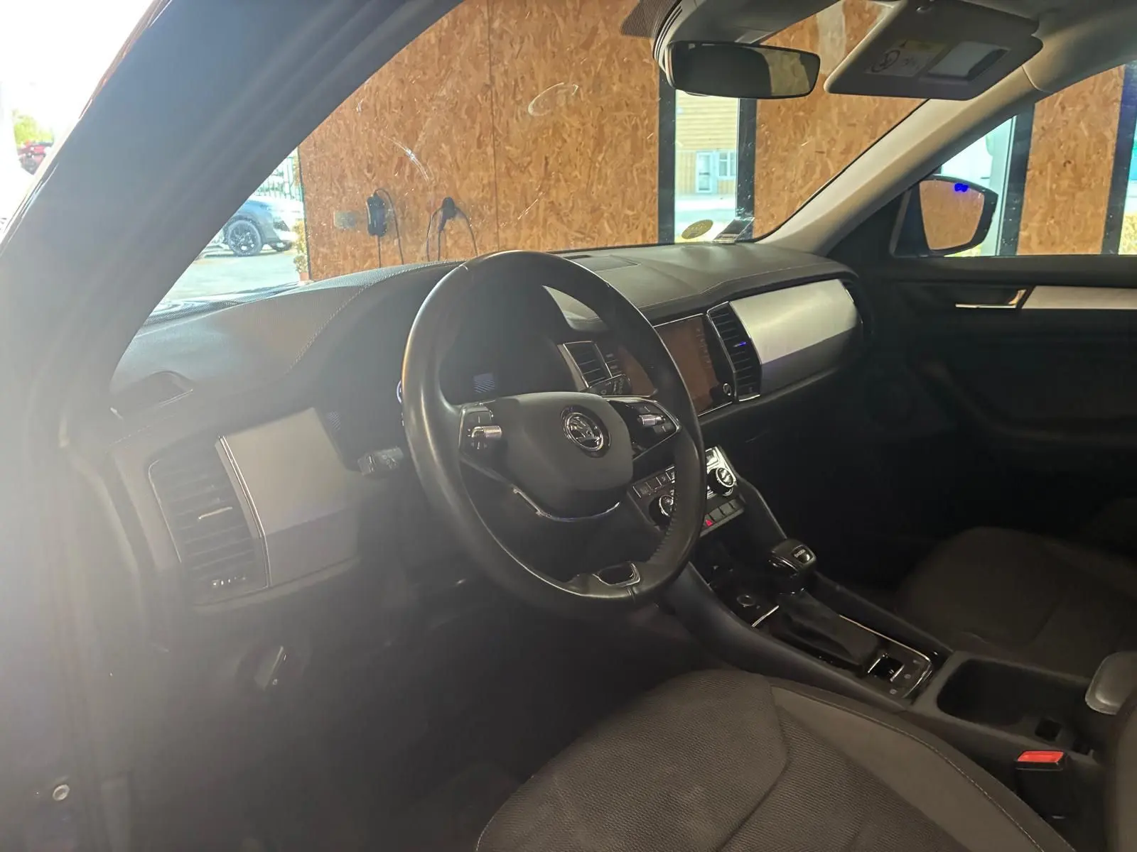 Intérieur noir du Skoda Kodiaq 2023, vue côté conducteur montrant le volant, tableau de bord et console centrale.