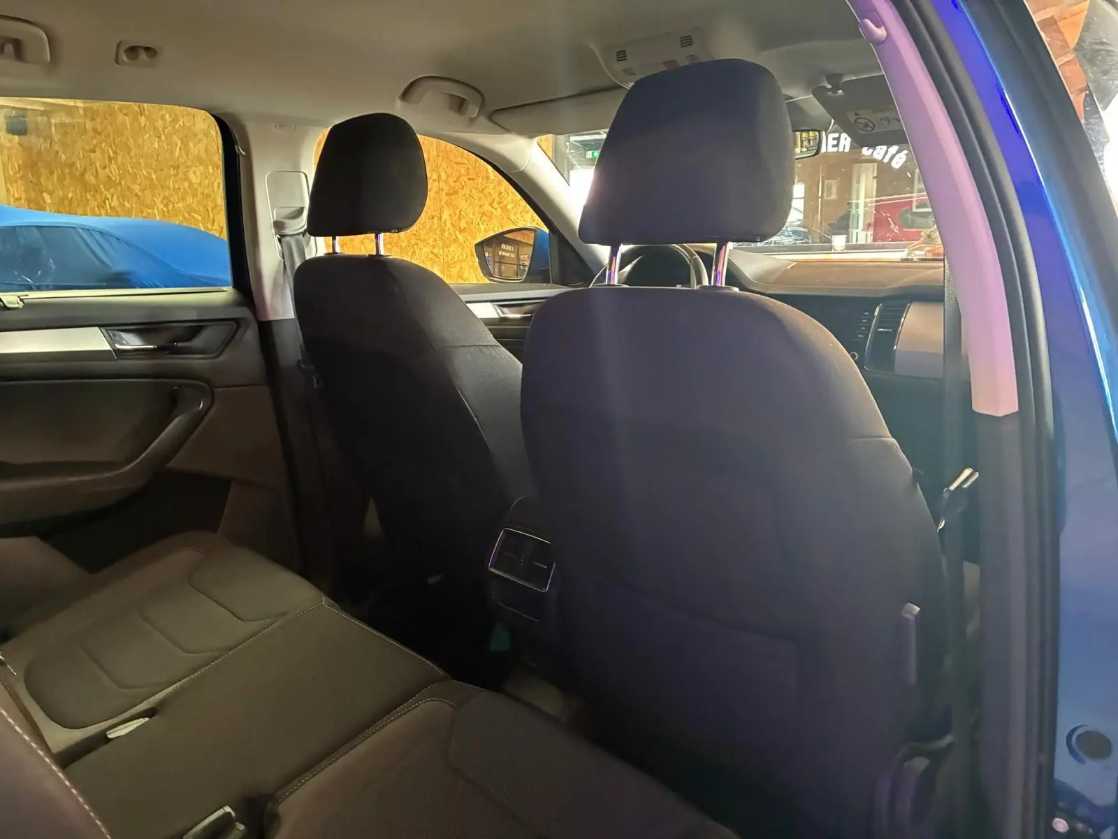 Vue intérieure arrière du Skoda Kodiaq bleu 2023, montrant les sièges noirs en tissu et la console centrale.
