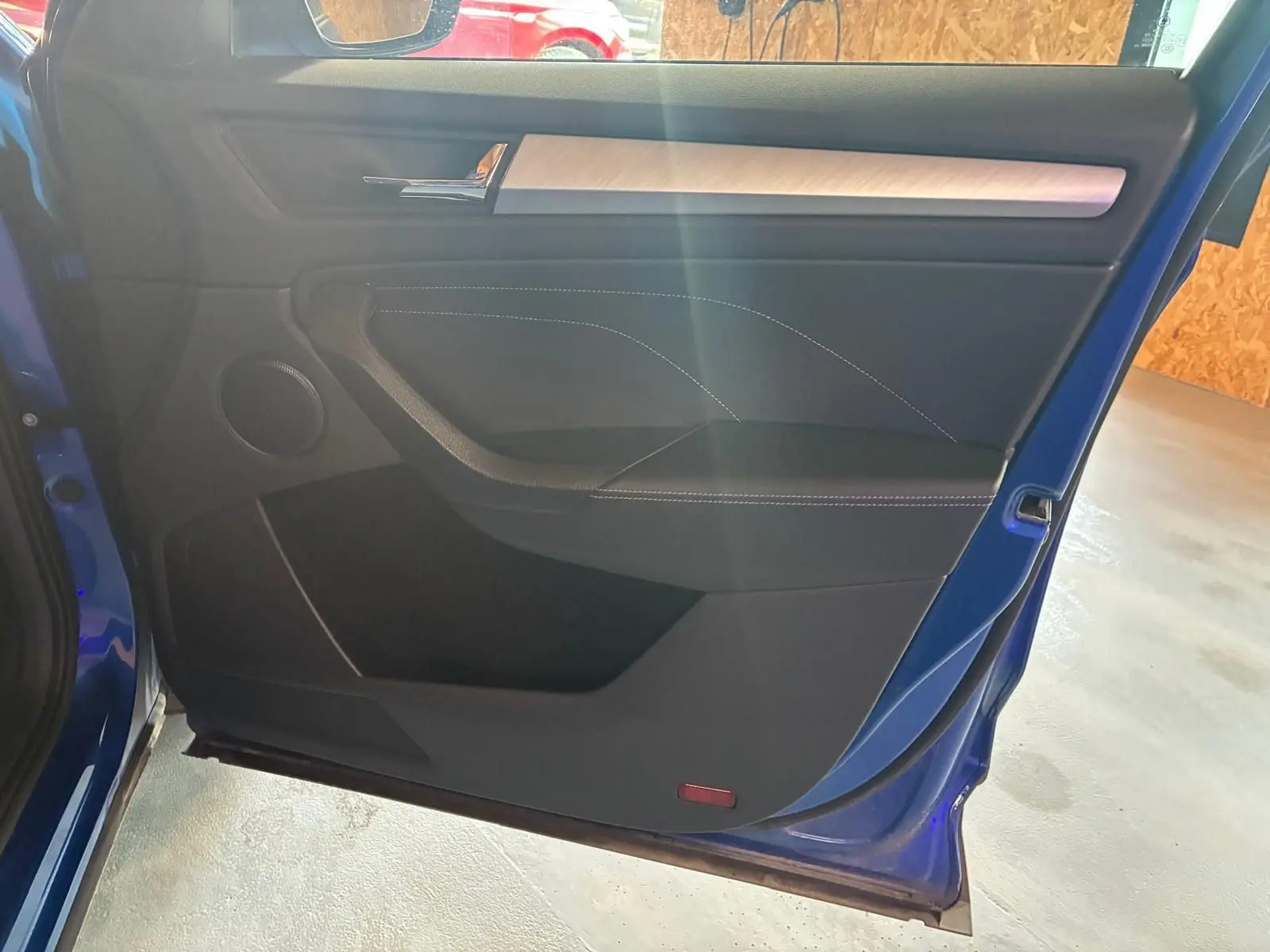 Vue intérieure de la porte avant gauche d’un Skoda Kodiaq bleu 2023, avec garniture noire et insert décoratif clair.