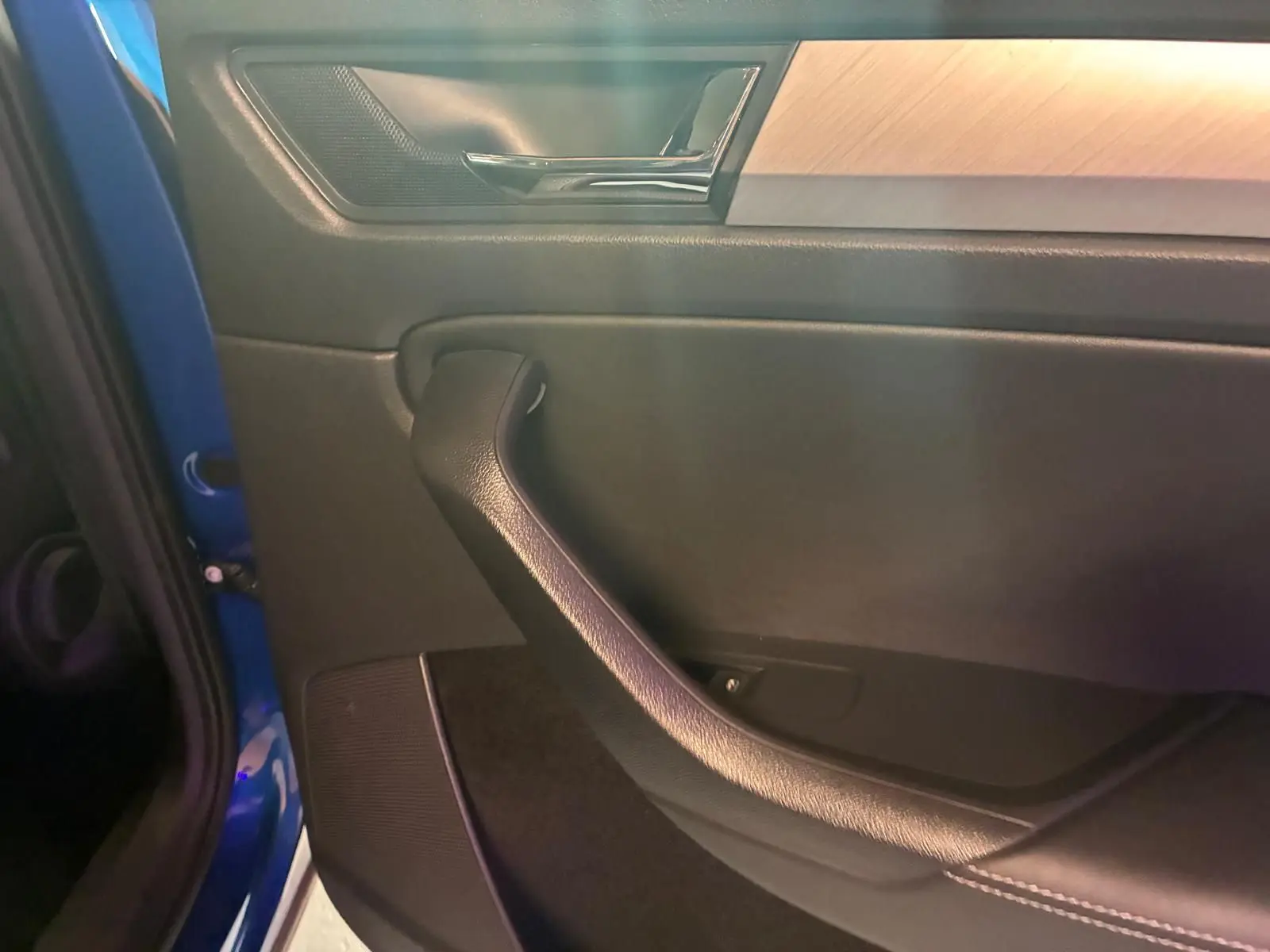 Détail de la porte côté gauche du Skoda Kodiaq 2023 bleu, avec poignée noire et insert décoratif bois clair.