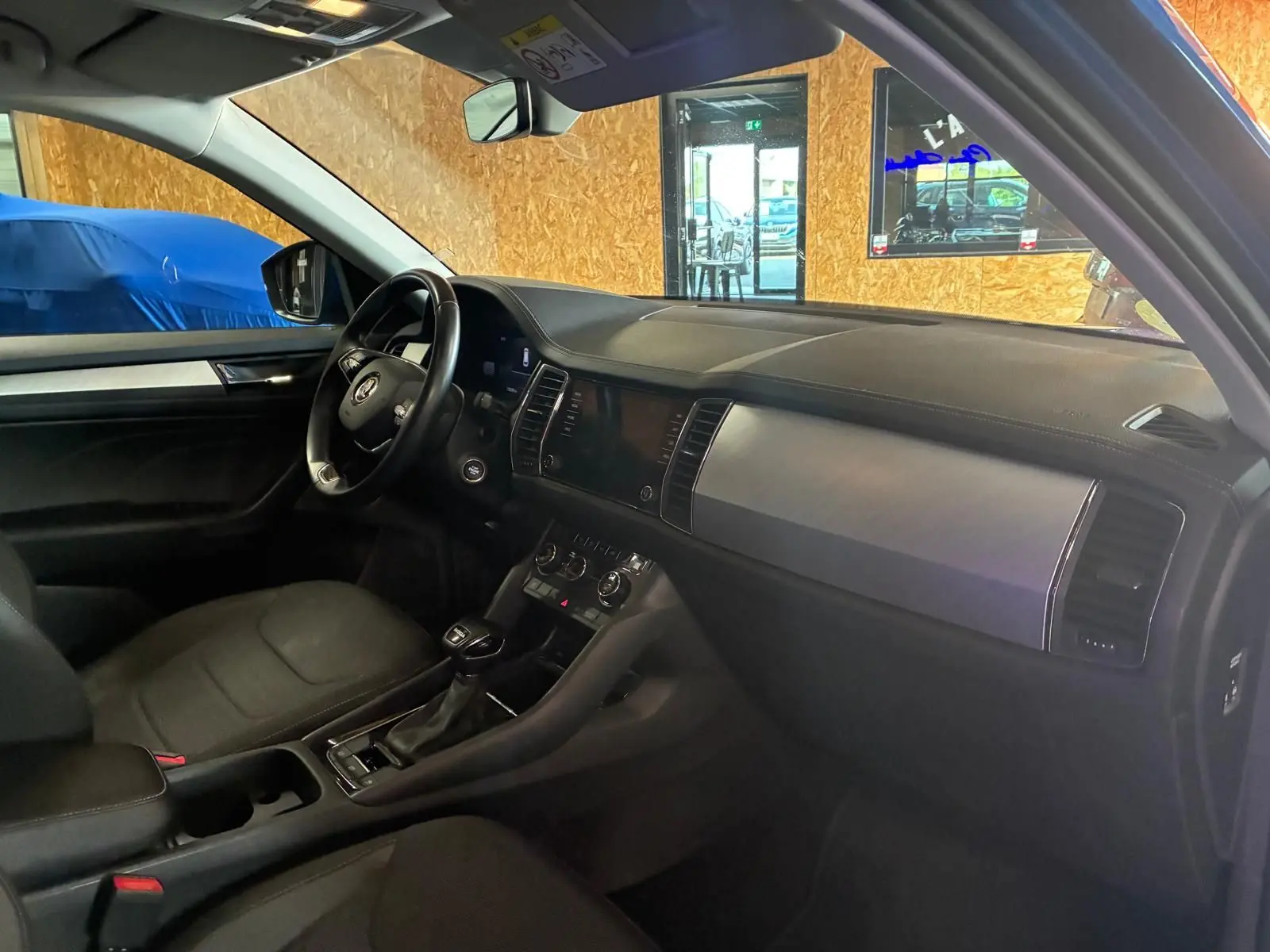 Vue intérieure côté conducteur du Skoda Kodiaq 2023, tableau de bord noir avec inserts métalliques et volant multifonction.