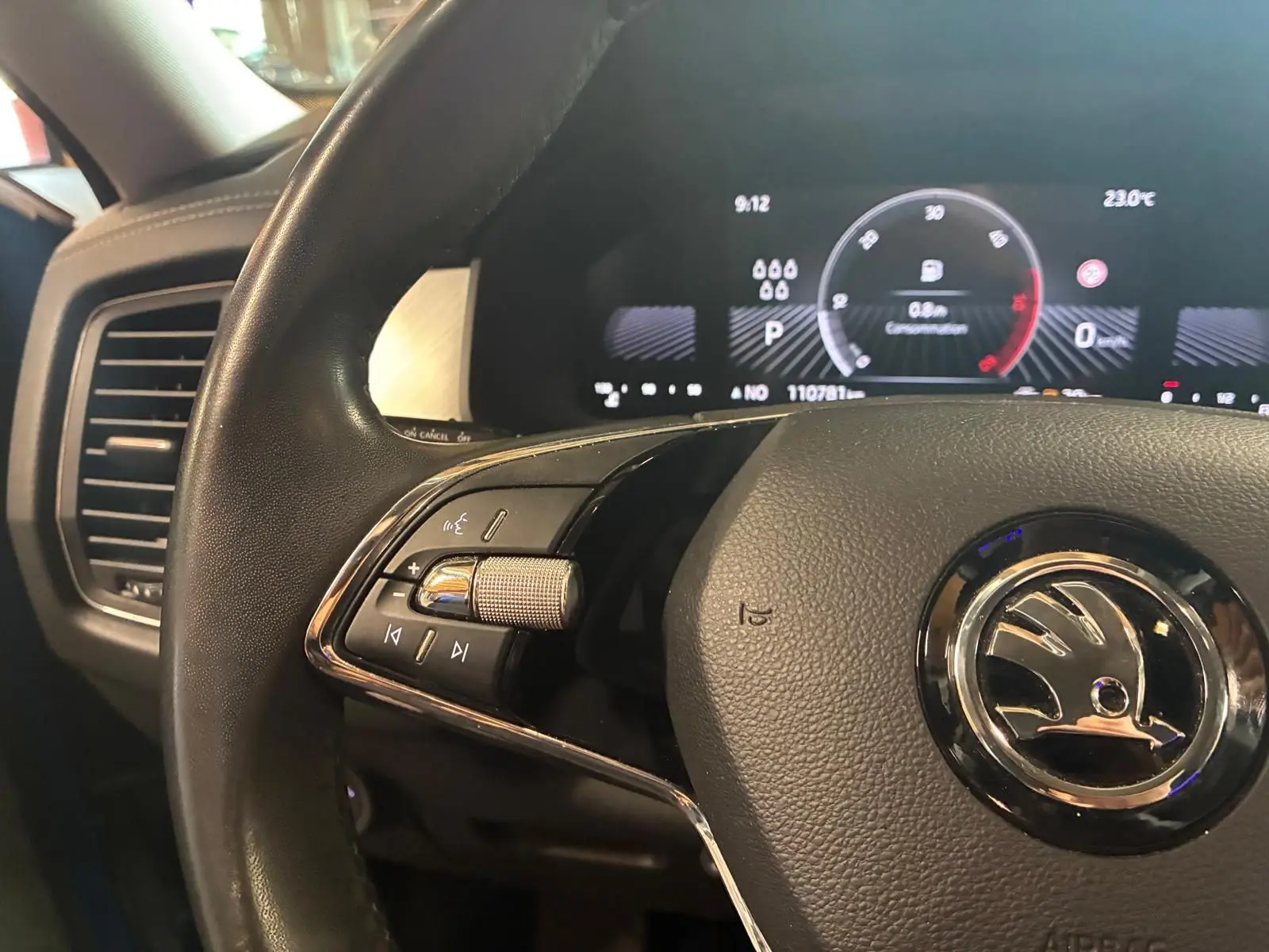 Gros plan sur le volant noir de la Skoda Kodiaq 2023 avec commandes intégrées et tableau de bord digital en arrière-plan.