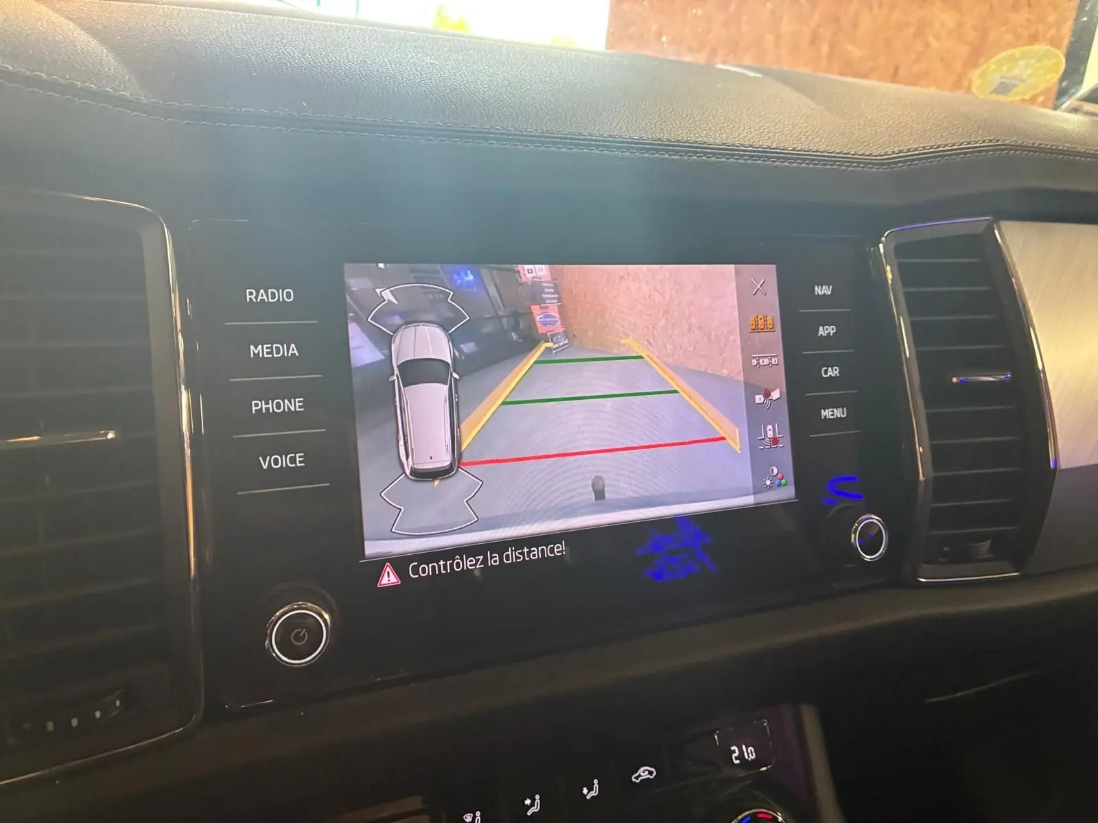 Écran central du Skoda Kodiaq 2023 montrant la caméra de recul avec lignes de guidage colorées.