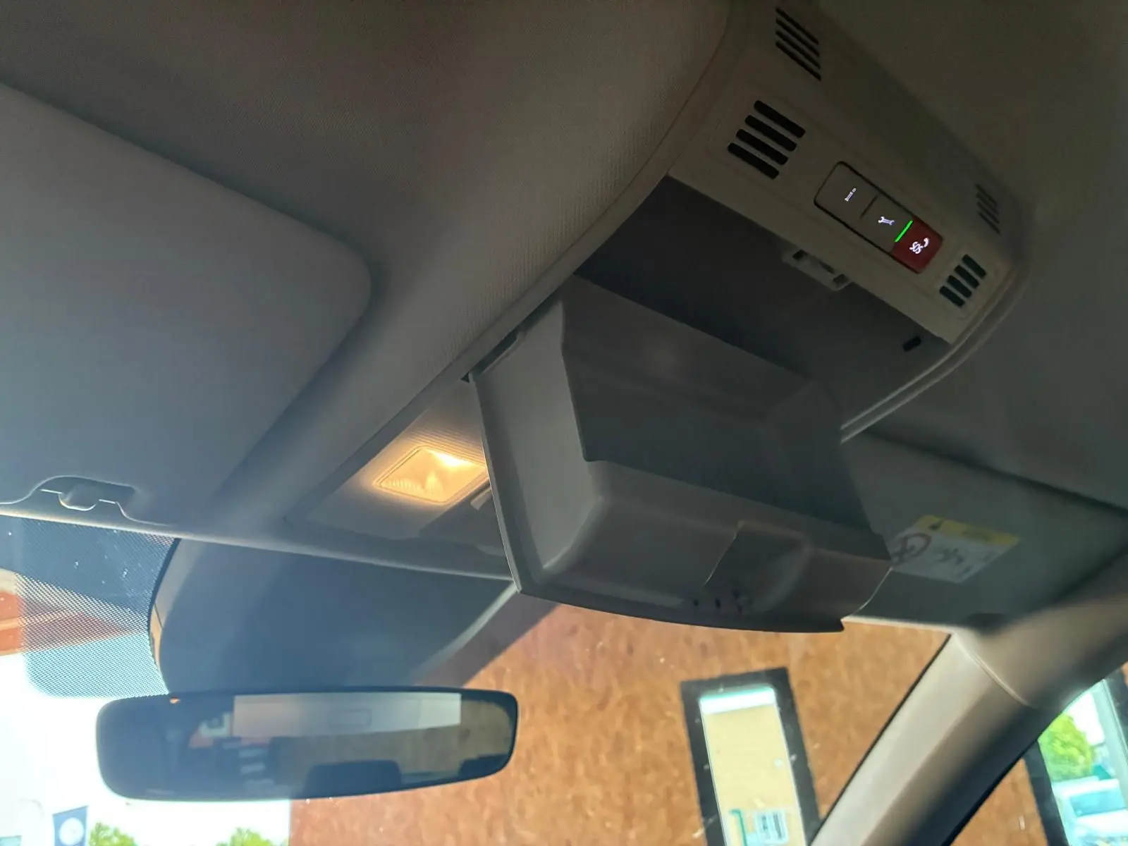 Vue intérieure du plafond avant d'un Skoda Kodiaq bleu 2023, avec rangement lunettes ouvert et éclairage allumé.
