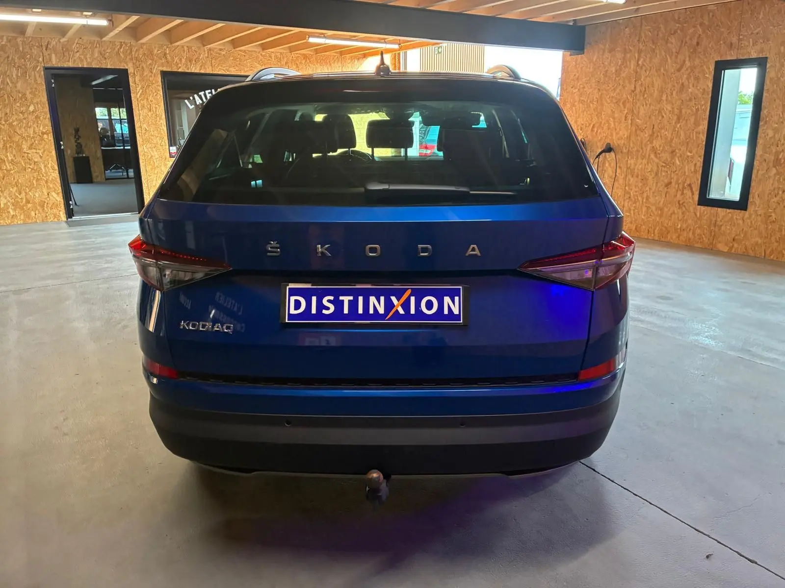 Vue arrière d'un Skoda Kodiaq bleu 2023 avec attelage et logo ŠKODA bien visible en intérieur.
