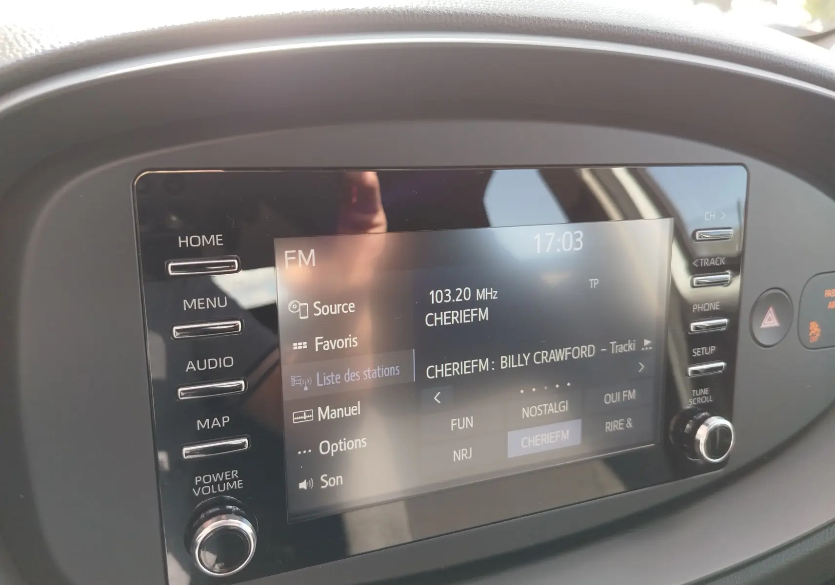 Vue rapprochée de l'écran multimédia tactile de la Toyota Aygo X 2023, affichant la radio FM sur fond noir.
