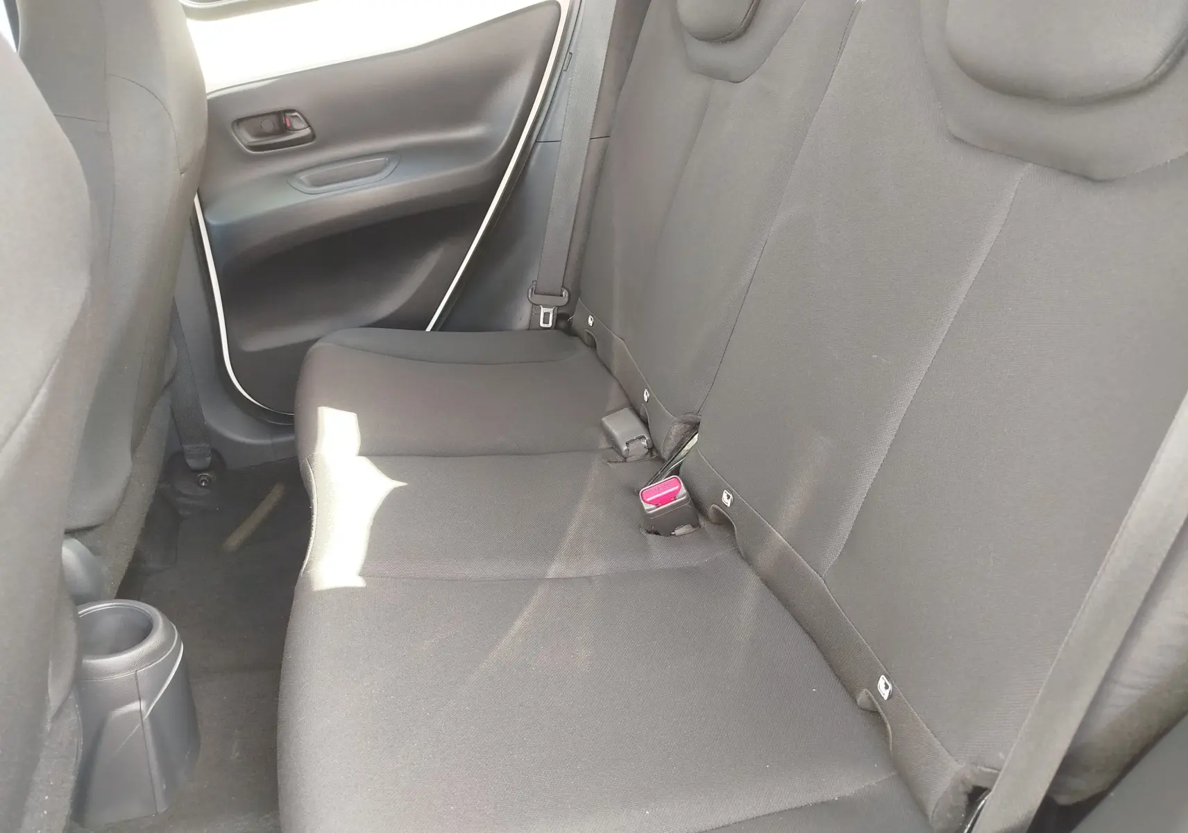 Vue intérieure côté droit des sièges arrière noirs d'une Toyota Aygo X 2023, avec ceinture et boucle de sécurité visibles.
