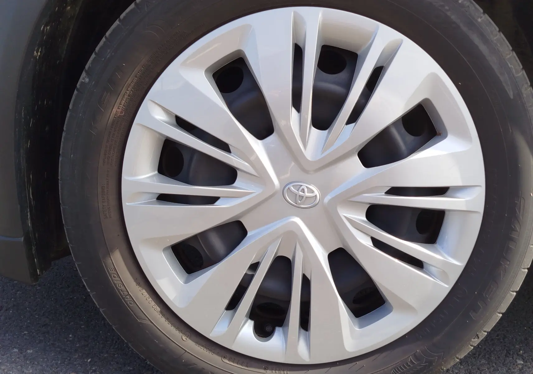 Gros plan sur la jante argentée avec logo Toyota au centre, montée sur un pneu noir du Toyota Aygo X blanc.