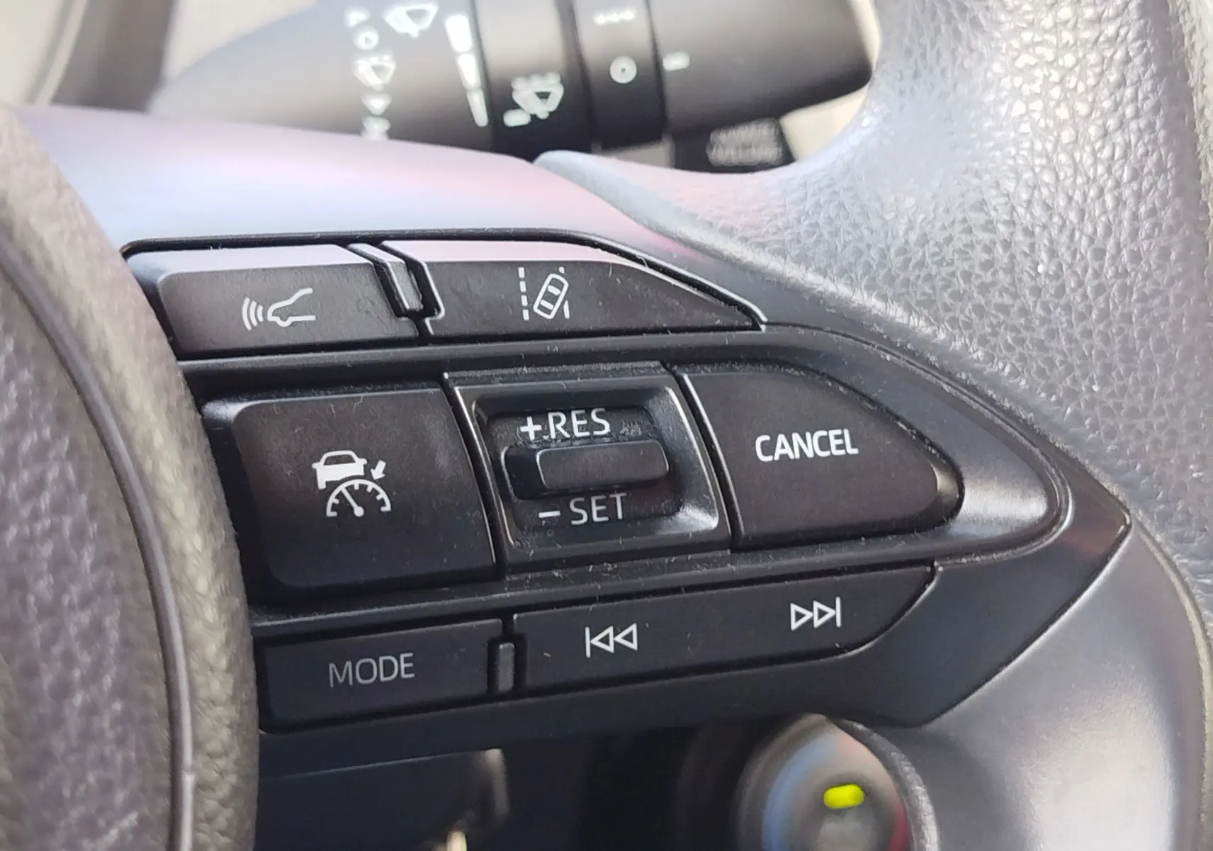 Gros plan sur les commandes de régulateur de vitesse au volant noir de la Toyota Aygo X blanche 2023.