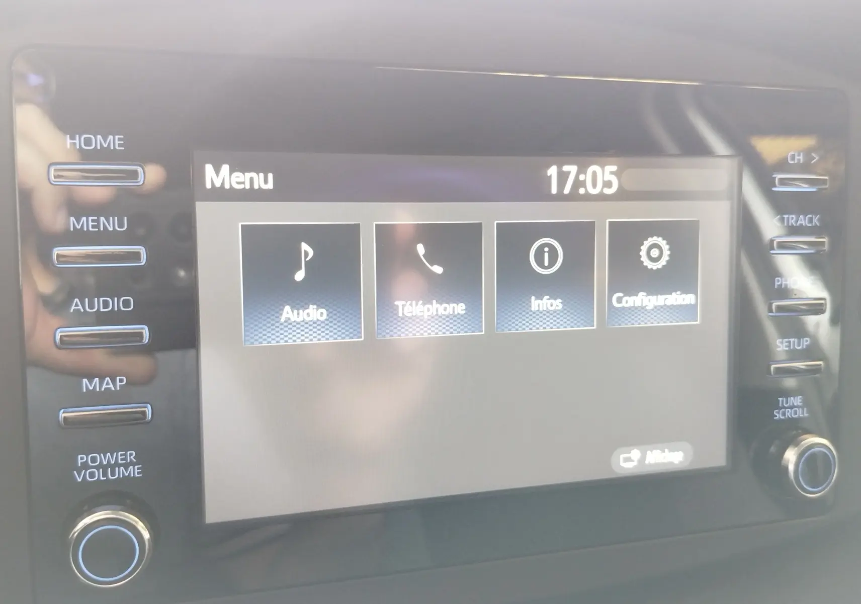 Écran tactile central de la Toyota Aygo X blanc, affichant le menu principal avec options audio, téléphone, infos et configuration.