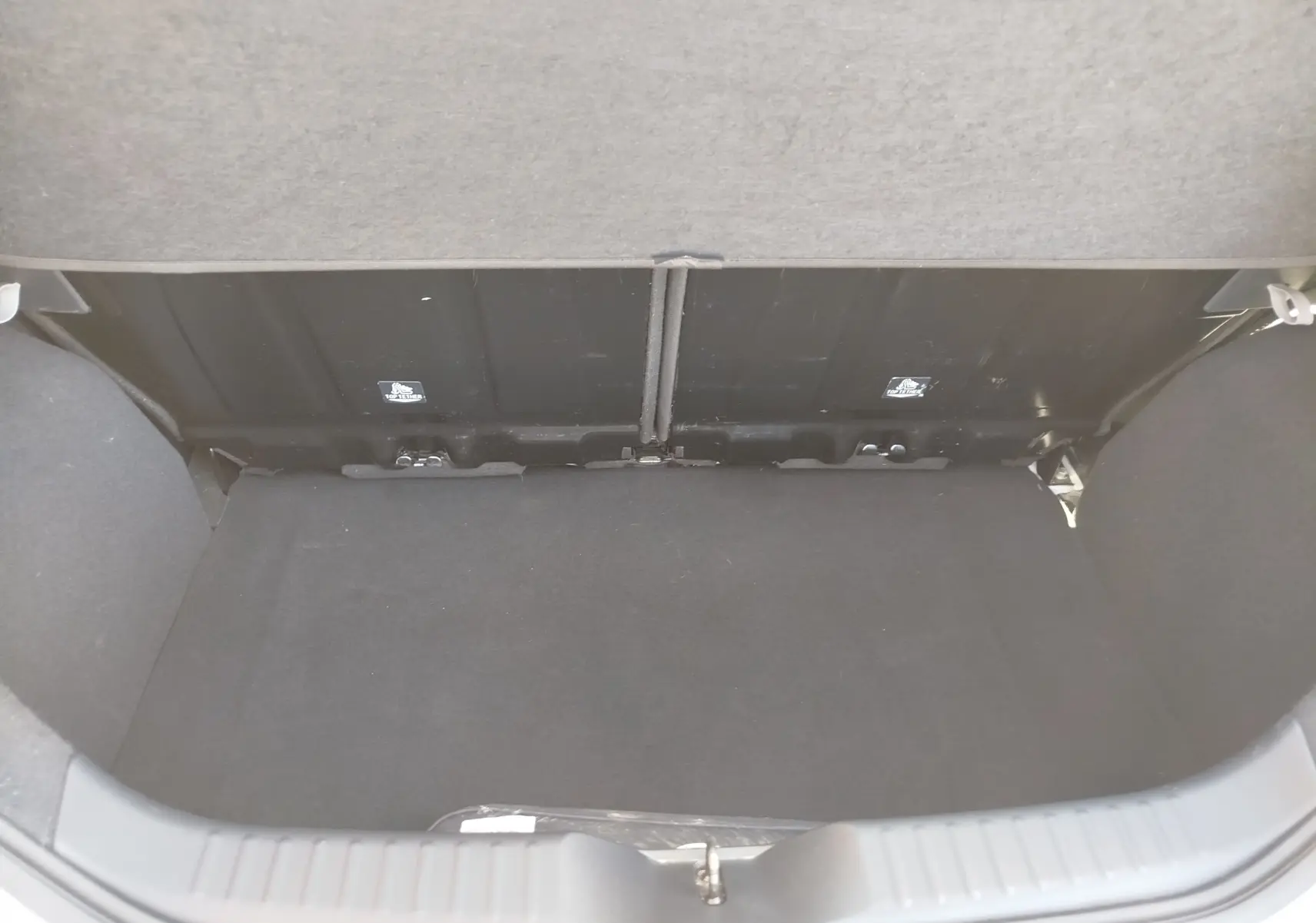 Vue intérieure du coffre noir de la Toyota Aygo X blanc pur, version 2023, avec banquette arrière visible.