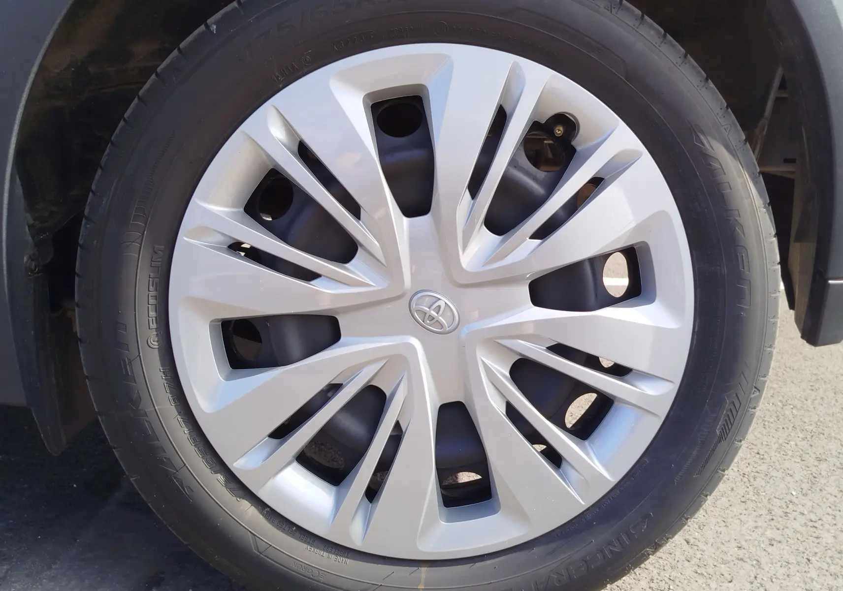 Gros plan sur la jante argentée avec logo Toyota au centre, montée sur un pneu noir de Toyota Aygo X blanc.